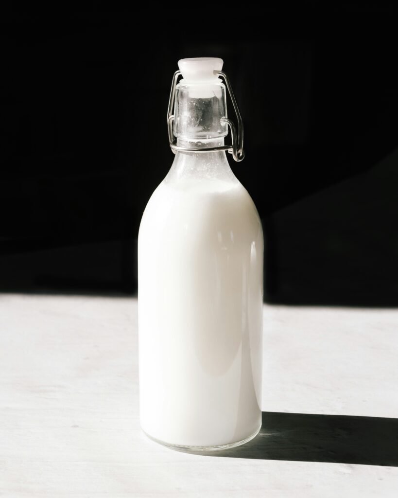 Clean Oat Milk Swaps - A pure glass bottle of homemade nut milk on a white surface representing additive-free labels